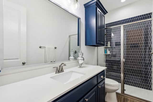 bathroom featuring vanity, toilet, wood-type flooring, and a shower with shower door