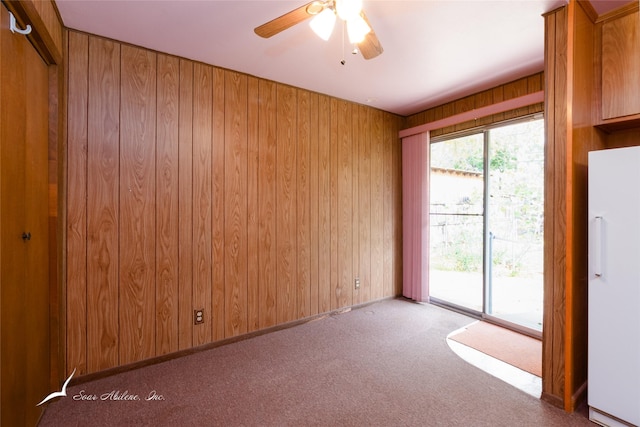 carpeted empty room featuring ceiling fan and wooden walls