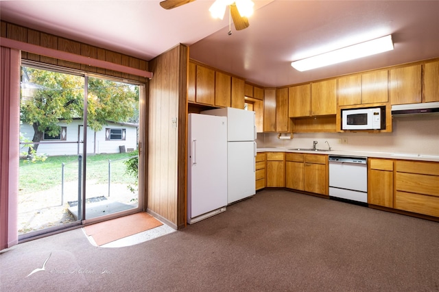 kitchen with wood walls, ceiling fan, dark carpet, and white appliances