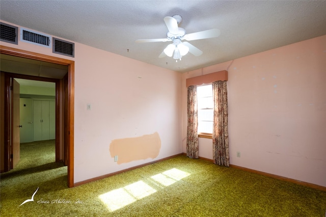 carpeted spare room featuring ceiling fan and a textured ceiling