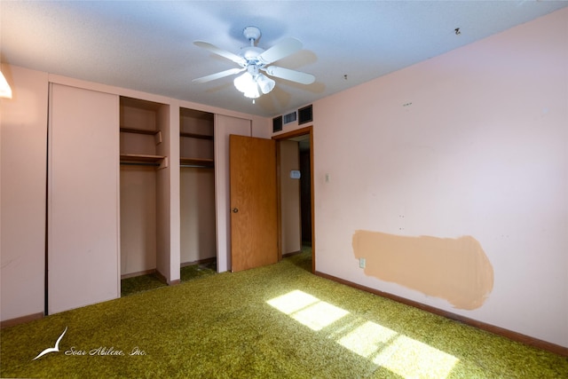 unfurnished bedroom featuring ceiling fan, dark carpet, and two closets