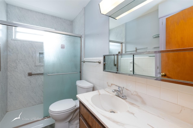 bathroom featuring backsplash, vanity, tile walls, toilet, and a shower with shower door