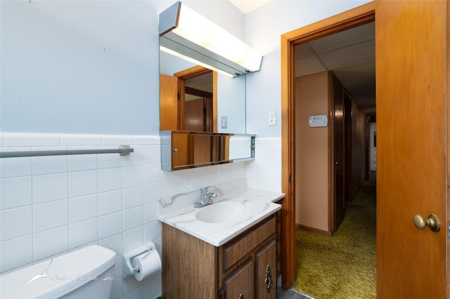 bathroom with vanity, toilet, and tile walls