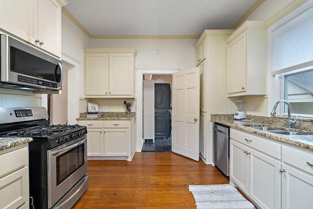 kitchen with sink, light stone counters, crown molding, appliances with stainless steel finishes, and hardwood / wood-style flooring