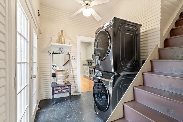 washroom featuring ceiling fan and stacked washer / dryer