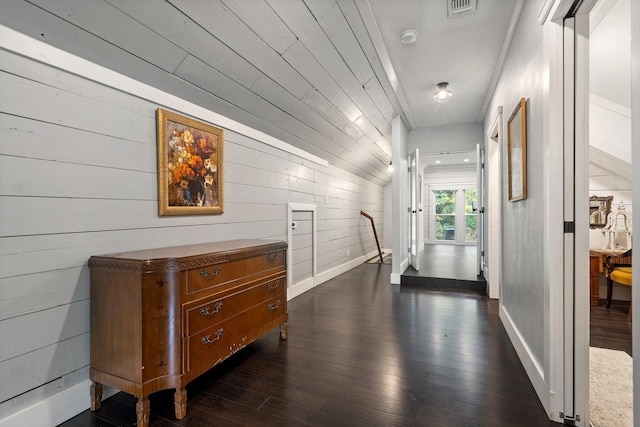 hallway with dark hardwood / wood-style flooring and wooden walls