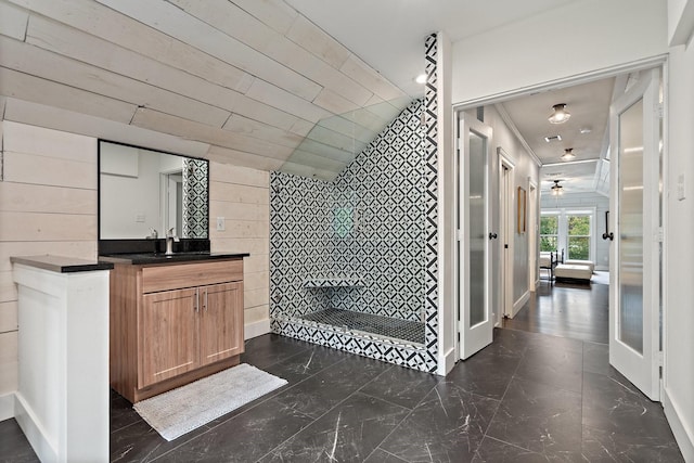 bathroom featuring a shower, vanity, ceiling fan, and wood walls