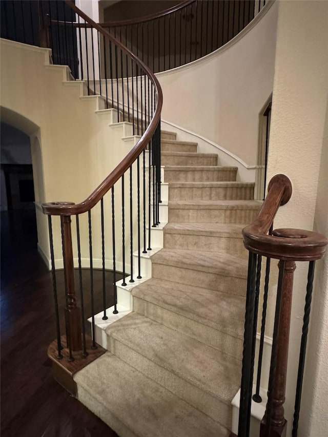 stairway with a high ceiling and hardwood / wood-style flooring