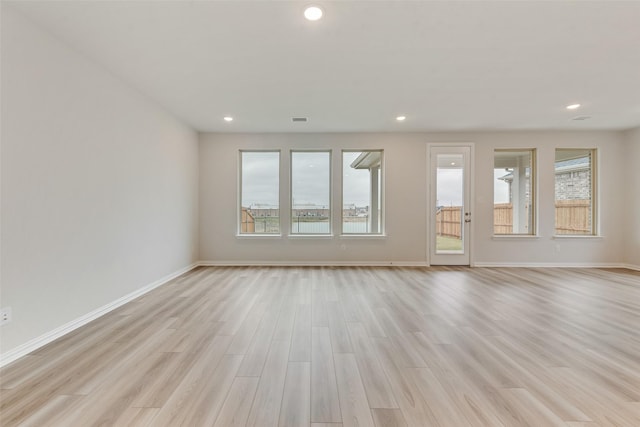 unfurnished room with a healthy amount of sunlight and light hardwood / wood-style floors