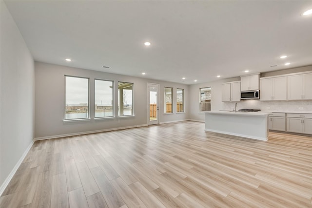 unfurnished living room with light hardwood / wood-style floors and sink