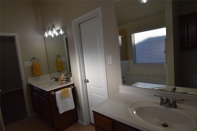 bathroom with a tub to relax in, vanity, and tile patterned flooring