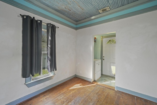 unfurnished room with hardwood / wood-style floors, washer / clothes dryer, and crown molding