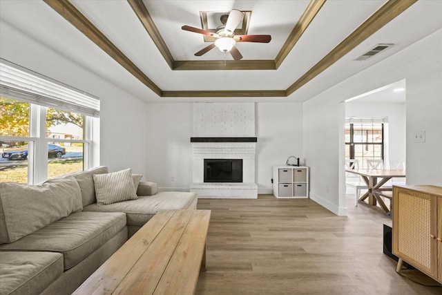 living room featuring a brick fireplace, ceiling fan, a healthy amount of sunlight, and hardwood / wood-style flooring