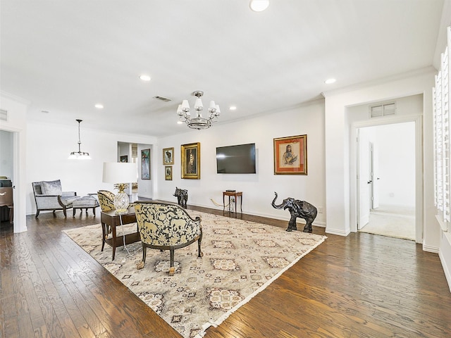 living room with crown molding, dark wood-type flooring, and an inviting chandelier