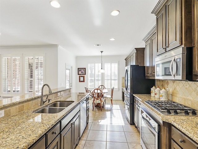 kitchen featuring appliances with stainless steel finishes, tasteful backsplash, dark brown cabinetry, sink, and light tile patterned flooring