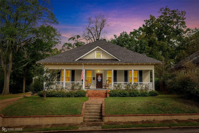 view of front of property with a porch and a yard