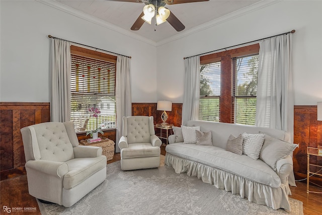 sitting room with a healthy amount of sunlight, a wainscoted wall, and crown molding