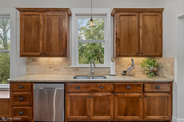 kitchen with stainless steel dishwasher, a sink, light stone counters, and tasteful backsplash