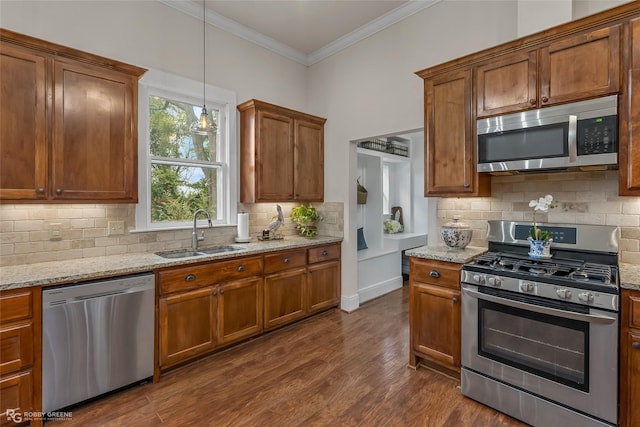 kitchen featuring light stone counters, dark wood finished floors, appliances with stainless steel finishes, ornamental molding, and a sink