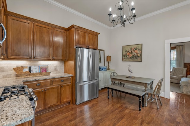 kitchen with ornamental molding, appliances with stainless steel finishes, brown cabinetry, and backsplash