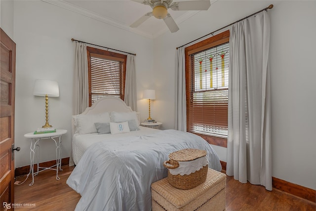 bedroom with crown molding, baseboards, ceiling fan, and wood finished floors