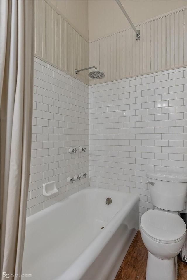 bathroom with toilet, shower / bath combo with shower curtain, and tile walls