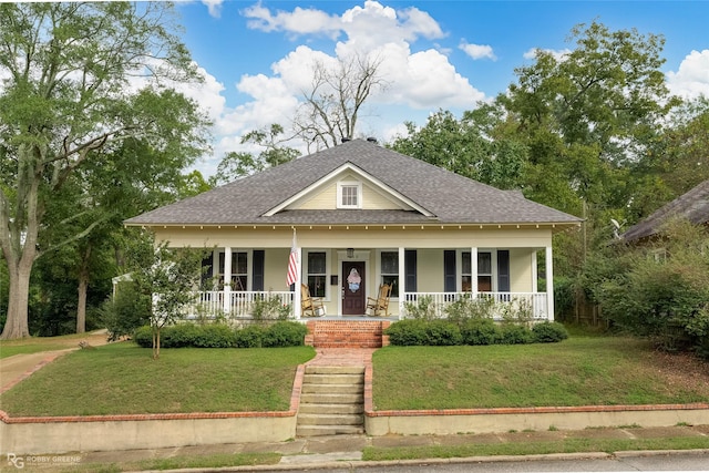 view of front of property with a porch, roof with shingles, and a front lawn