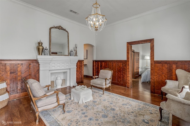 living area with a brick fireplace, wainscoting, visible vents, and a notable chandelier