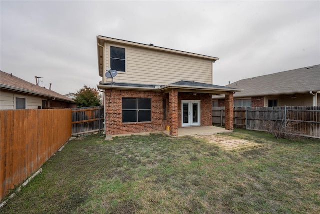 back of house featuring a lawn, a patio, and french doors