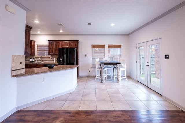 kitchen with decorative backsplash, french doors, black appliances, stone countertops, and light hardwood / wood-style flooring