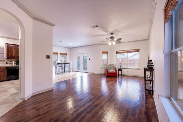 living room featuring french doors, ceiling fan, ornamental molding, a textured ceiling, and light hardwood / wood-style floors