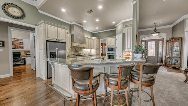 kitchen with a breakfast bar, appliances with stainless steel finishes, light stone counters, decorative light fixtures, and custom exhaust hood