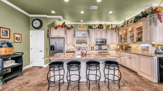 kitchen featuring stainless steel appliances, crown molding, a kitchen island, and light stone countertops