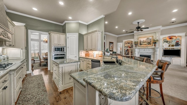 kitchen featuring a spacious island, a breakfast bar, sink, appliances with stainless steel finishes, and kitchen peninsula