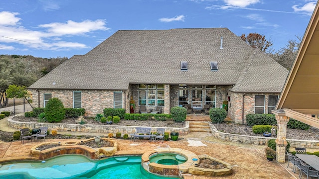 rear view of property featuring a swimming pool with hot tub and a patio