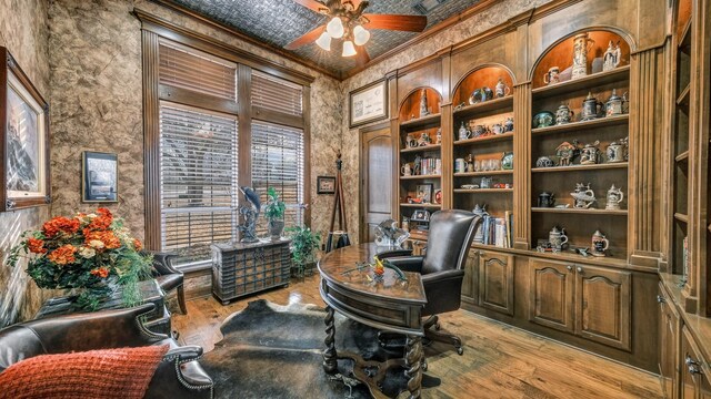 home office with built in shelves, ceiling fan, ornamental molding, and light wood-type flooring