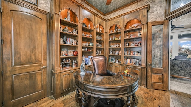 home office featuring hardwood / wood-style floors, built in shelves, ornamental molding, and ceiling fan