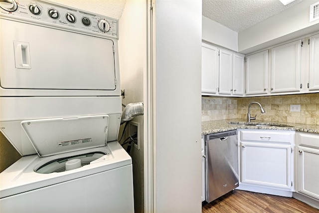 washroom featuring stacked washer and dryer, light hardwood / wood-style floors, sink, and a textured ceiling