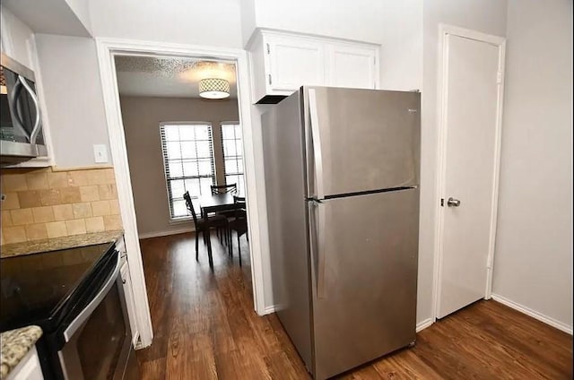 kitchen with white cabinetry, tasteful backsplash, dark hardwood / wood-style floors, and appliances with stainless steel finishes