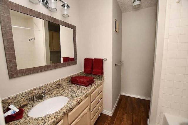 bathroom with hardwood / wood-style flooring, vanity, tub / shower combination, and a textured ceiling