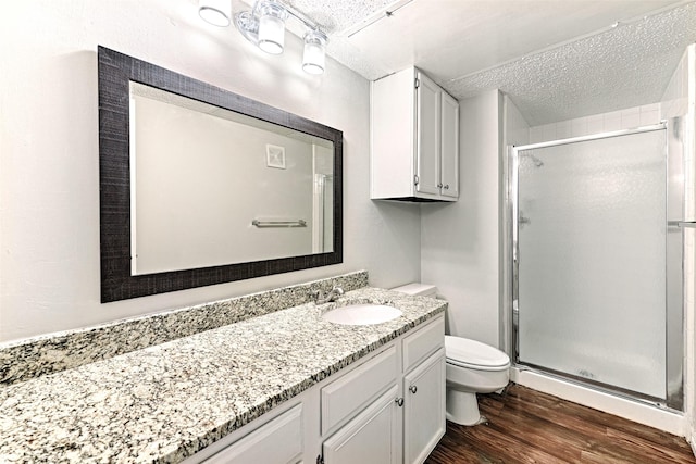 bathroom featuring vanity, hardwood / wood-style floors, a shower with shower door, and toilet