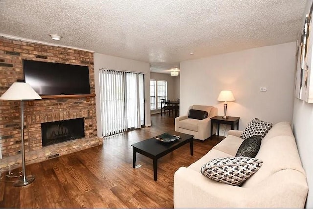 living room with hardwood / wood-style floors, a brick fireplace, and a textured ceiling