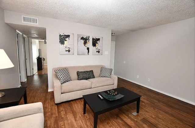 living room featuring dark wood-type flooring and a textured ceiling