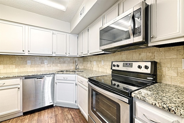 kitchen with stainless steel appliances, sink, hardwood / wood-style floors, and white cabinets