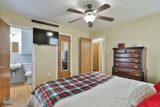 bedroom with light hardwood / wood-style floors, ensuite bath, ceiling fan, and sink