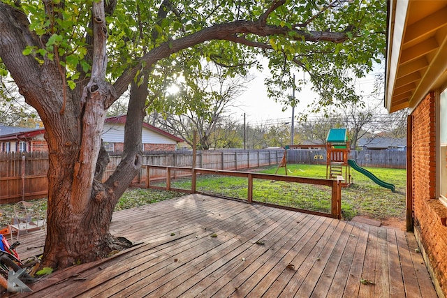 wooden deck featuring a playground and a lawn