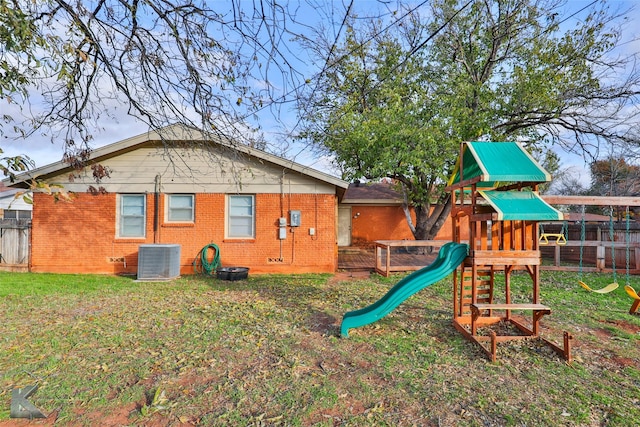 back of house with a lawn, a playground, and central AC