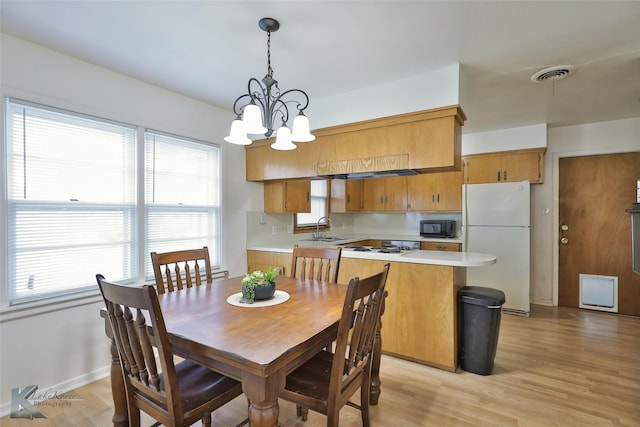 dining area featuring a chandelier, sink, and light hardwood / wood-style flooring