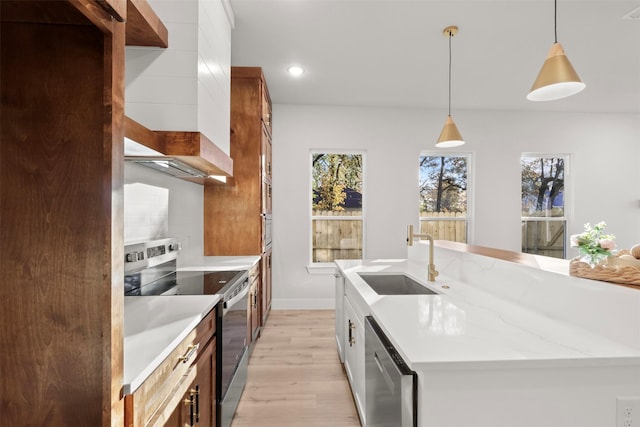 kitchen featuring pendant lighting, sink, a kitchen island with sink, stainless steel appliances, and light stone counters