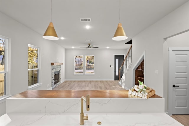 living room featuring light hardwood / wood-style flooring, a tile fireplace, and ceiling fan